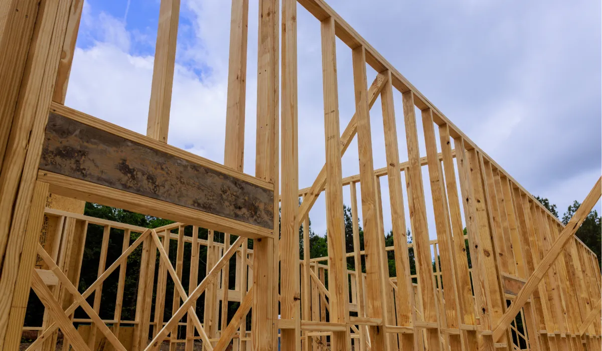 Wooden framing of a house under construction against a partly cloudy sky.