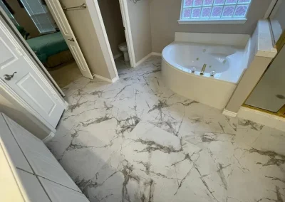 Bathroom with marble-patterned floor, a corner bathtub, glass shower, and a toilet in a separate alcove.