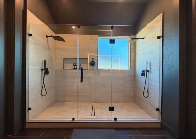 Spacious modern double shower with glass doors, black fixtures, and a frosted window in the center.